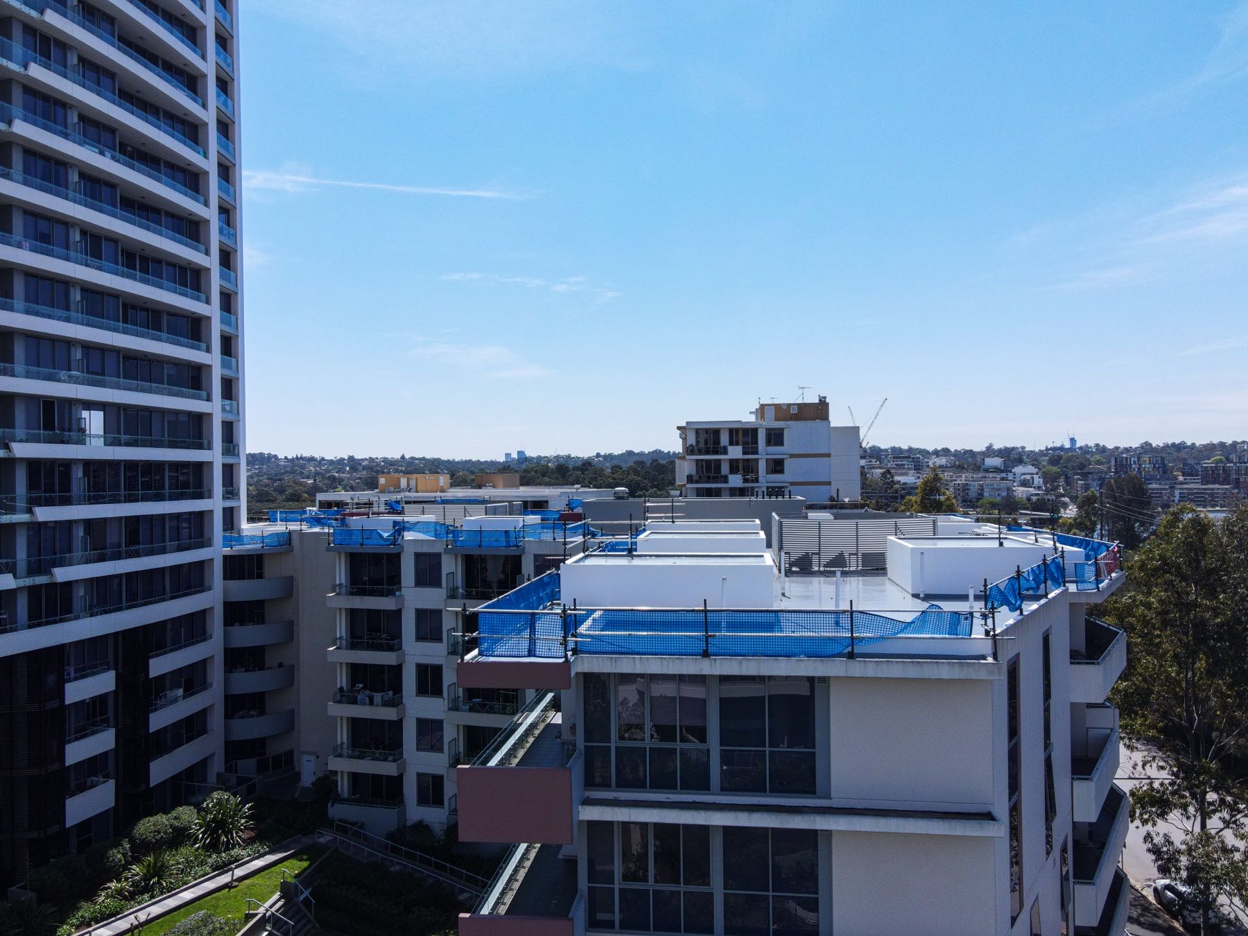 Drone photo at roof height of blue edge protection mesh around an apartment rooftop in Rhodes